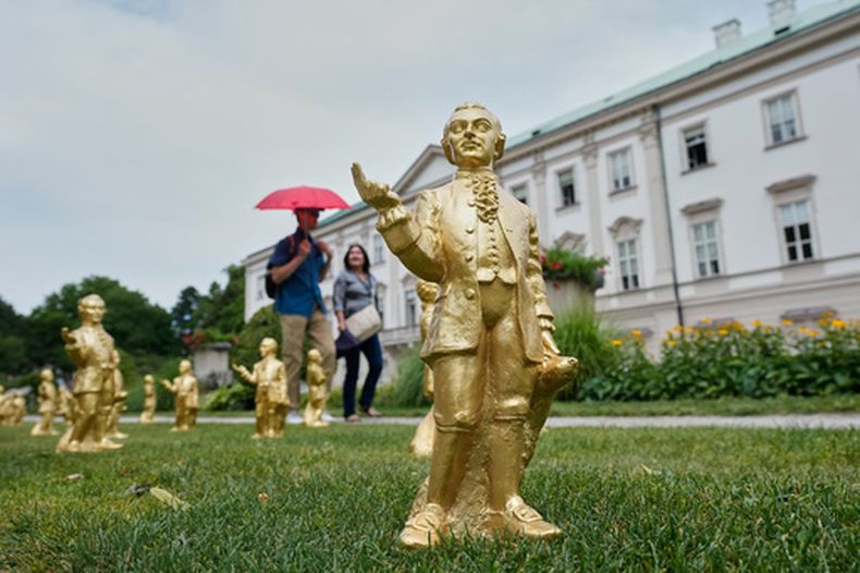 ARCHIVO - Personas pasan junto a algunas de las 400 estatuillas de plástico dorado de Mozart, obra del artista alemán Ottmar Hoerl, de Núremberg, con motivo del 270.º aniversario del nacimiento del compositor Wolfgang Amadeus Mozart, en Salzburgo, Austria, el miércoles 15 de julio de 2026. (Foto AP/Matthias Schrader, archivo)