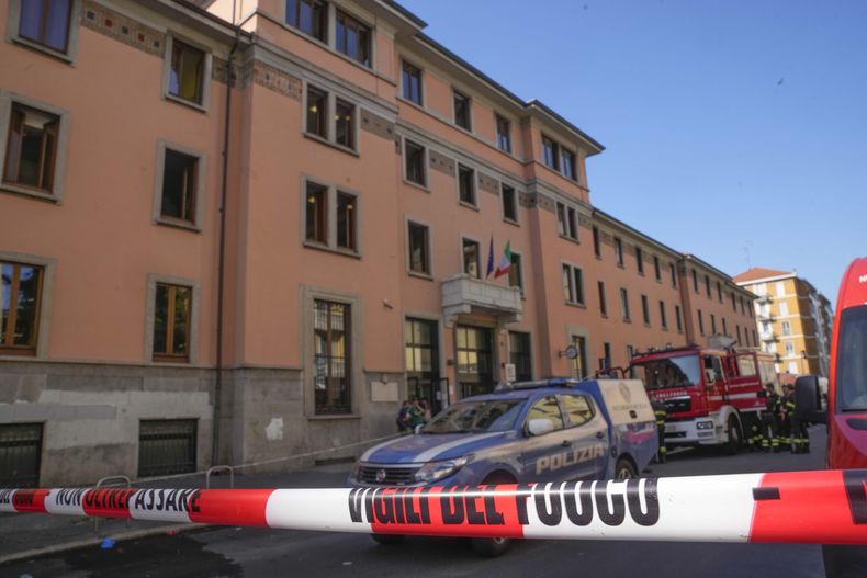 Un camión del Departamento de Bomberos y una camioneta de la policía se encuentran estacionados frente al asilo de ancianos Casa per Coniugi, donde se registró un incendio, en Milán, Italia, el viernes 7 de julio de 2023. (AP Foto/Antonio Calanni)