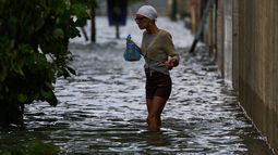 Una mujer camina por una calle inundada el domingo 1 de febrero de 2026, en La Habana. (AP Foto/Ramón Espinosa)