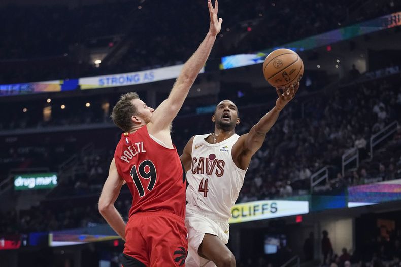 El alero de los Cavaliers de Cleveland Evan Mobley (4) lanza frente al centro de los Raptors de Toronto Jakob Poeltl (19) en la primera mitad del juego de NBA, el domingo 26 de noviembre, en Cleveland. (AP Foto/Sue Ogrocki)