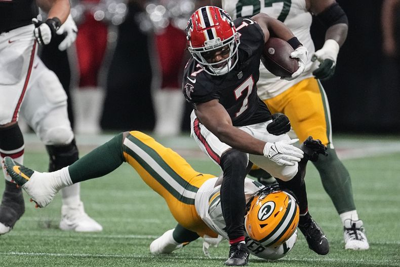 El running back Bijan Robinson (7) de los Falcons de Atlanta corre por encima de Quay Walker de los Packers de Green Bay, el domingo 17 de septiembre de 2023, en Atlanta. (AP Foto/John Bazemore)