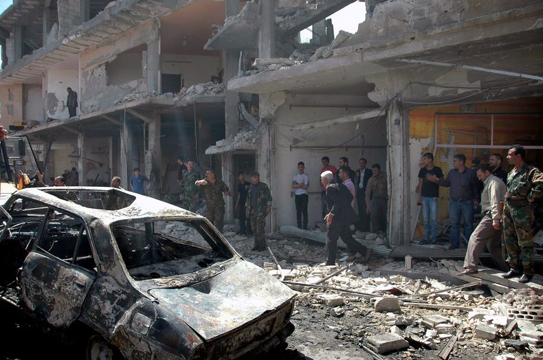 Fotograf&iacute;a distribuida por la agencia oficial de noticias siria SANA muestra gente reunida en el sitio donde estall&oacute; uno de dos carros bomba en el distrito de Zahra, en la ciudad de Homs, Siria, el martes 29 de abril de 2014. (Foto AP/SANA)