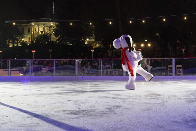 Con la Casa Blanca decorada para las festividades navideñas al fondo, Snoopy patina sobre la pista de hielo de la Casa Blanca, ubicada en el patio sur del complejo, el miércoles 29 de noviembre de 2023, durante la ceremonia de presentación de la pista en Washington. (AP Foto/Jacquelyn Martin)