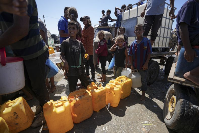 Palestinos desplazados hacen fila para obtener agua, en Deir al Balah, en la Franja de Gaza, el viernes 23 de agosto de 2024. (AP Foto/Abdel Kareem Hana)