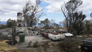Vehículos calcinados se ven junto a una casa destruida por los incendios el lunes 14 de agosto de 2023, en Kula, Hawai. El mismo día que un incendio devastó la localidad de Lahaina, otro golpeó la población de Kula. (AP Foto/Rick Bowmer)