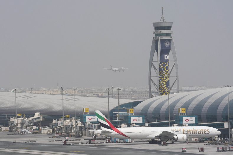 ARCHIVO - Un Boeing 777 de Emirates, en una de las puertas del aeropuerto internacional de Dubái, mientras otro avión se prepara para aterrizar en la pista, en Dubái, Emiratos Árabes Unidos, el 17 de agosto de 2022. (AP Foto/Jon Gambrell, archivo)