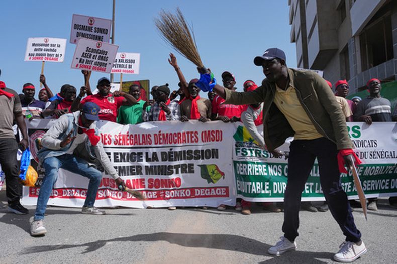 Trabajadores portan pancartas y carteles en una marcha para exigir que el gobierno cumpla sus compromisos y atienda sus preocupaciones, el miércoles 8 de abril de 2026, en Dakar, Senegal. (AP Foto/Misper Apawu)