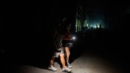 Varias personas caminan por una calle iluminadas con linternas durante un apagón en La Habana, Cuba, el lunes 6 de julio de 2026. (AP Foto/Ramón Espinosa)