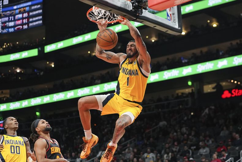 El alero de los Pacers de Indiana Obi Toppin (1) anota mientras el base de los Hawks de Atlanta Patty Mills (8) defiende durante la segunda mitad del juego de baloncesto de la NBA, el viernes 12 de enero de 2024, en Atlanta. (AP Foto/John Bazemore)