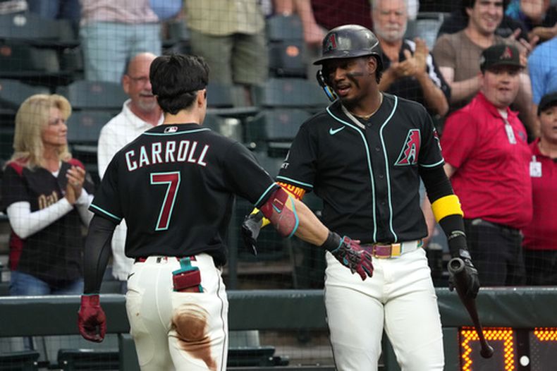 Corbin Carroll (7), de los Diamondbacks de Arizona, celebra con Geraldo Perdomo (derecha) tras conectar un triple y anotar por un error en la primera entrada de un partido de béisbol contra los Gigantes de San Francisco, el martes 19 de mayo de 2026, en Phoenix. (Foto AP/Rick Scuteri) CORRECCIÓN: Corrige la fecha a 19 de mayo en lugar del 20 de mayo.