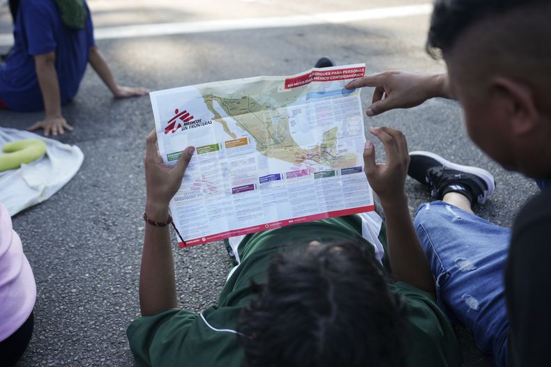 Migrantes que forman parte de una caravana que marcha hacia la frontera norte de México y, en última instancia, hacia Estados Unidos, revisan un mapa durante un descanso a las afueras de Escuintla, en el sur de México, el 7 de noviembre de 2024. (AP Foto/Moisés Castillo)