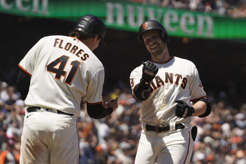 Austin Slater, a la derecha, es felicitado por su compañero de los Gigantes de San Francisco, el venezolano Wilmer Flores, después de conectar un jonrón de dos carreras en el quinto inning del partido ante los Rockies de Colorado, el sábado 8 de julio de 2023, en San Francisco. (AP Foto/Eric Risberg)