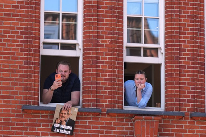 Dos personas miran por la ventana en las inmediaciones del sitio donde dos personas fueron apuñaladas en la víspera, en el vecindario de Golders Green, que alberga una numerosa comunidad judía, en Londres, el 30 de abril de 2026. (AP Foto/Alastair Grant)