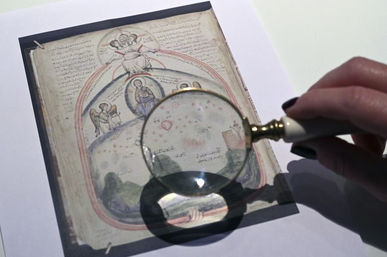Christina Sotirakoglou, una experta en caligrafía, observa pinturas bizantinas en fotografías impresas, en su oficina en Salónica, en el norte de Grecia, el 30 de noviembre de 2024. (AP Foto/Giannis Papanikos)