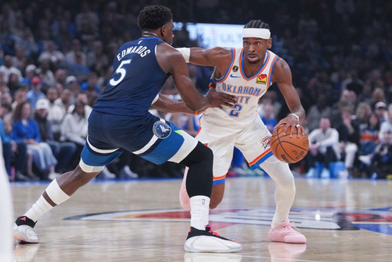 Shai Gilgeous-Alexander (derecha), del Thunder de Oklahoma City, rebasa al base Anthony Edwards (5), de los Timberwolves de Minnesota, durante la primera mitad de un juego de baloncesto de la NBA, el domingo 15 de marzo de 2026, en Oklahoma City. (Foto AP/Kyle Phillips)