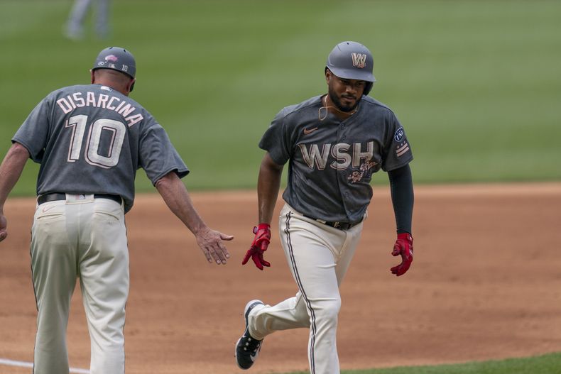 Jeimer Candelario de los Nacionales de Washington celebra con el entrenador de tercera base Gary Disarcina tras pegar un jonrón en la primera entrada en el juego ante los Rangers de Texas el sábado 8 de julio del 2023. (AP Foto/Stephanie Scarbrough)