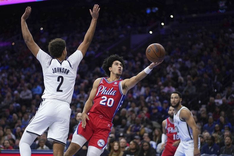 Jared McCain (20), de los 76ers de Filadelfia, toma un tiro dejando atrás la marca defensiva de Cameron Johnson (2), de los Nets de Brooklyn, durante la segunda mitad del juego de baloncesto de la NBA Cup, el viernes 22 de noviembre de 2024, en Filadelfia. (AP Foto/Matt Slocum)