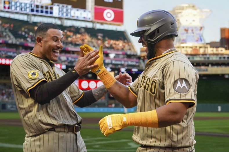 El venezolano Elías Díaz (derecha), de los Padres de San Diego, festeja con el dominicano Manny Machado luego de batear un jonrón ante los Mellizos de Minnesota, el sábado 30 de agosto de 2025 (AP Foto/Craig Lassig)