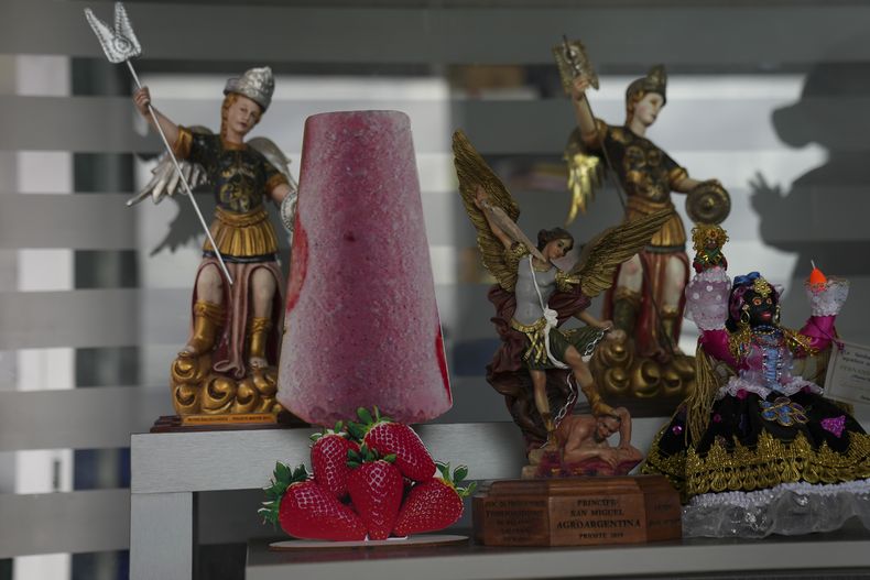 Una silueta de paleta en cartón adorna un estante junto a una figura del arcángel san Miguel, patrón de Salcedo, en Ecuador, el jueves 28 de noviembre de 2024, durante una sucesión de apagones provocados por una prolongada sequía. (AP Foto/Dolores Ochoa)