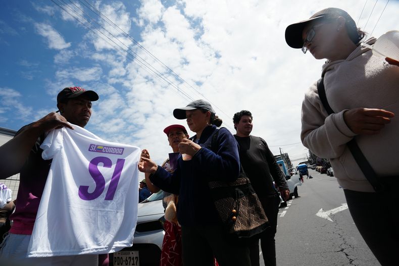 Un partidario del sí en un referéndum sobre la autorización de bases militares extranjeras y la convocatoria de una Asamblea Constituyente para redactar una nueva Constitución, reparte camisetas en Quito, Ecuador, el miércoles 12 de noviembre de 2025. (AP Foto/Dolores Ochoa)