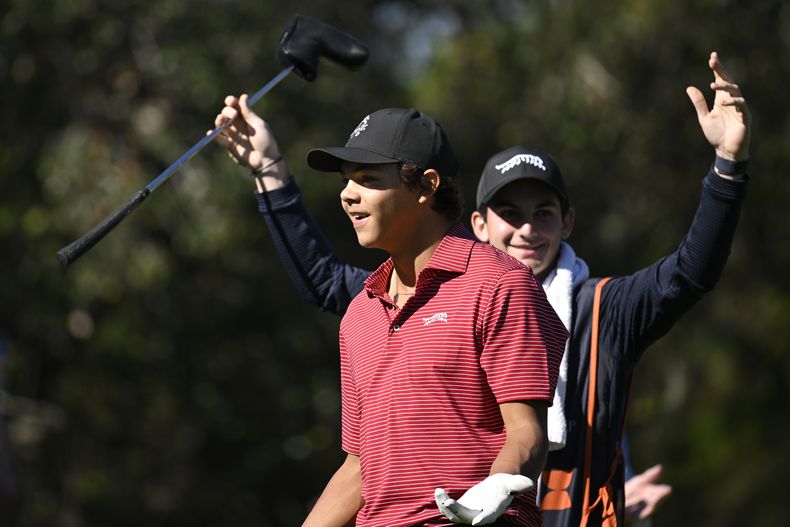 Charlie Woods, al frente, y su caddie, Luke Wise, reacciona después de que lograra un hoyo en uno durante la última ronda del torneo de golf Campeonato PNC, el domingo 22 de diciembre de 2024, en Orlando, Florida. (AP Foto/Phelan M. Ebenhack)