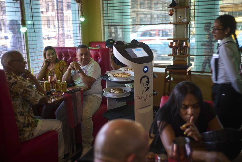 Los clientes observan cómo un robot llega con su comida al restaurante Doña Alicia en La Habana, el miércoles 15 de abril de 2025. (AP Foto/Ramón Espinosa)