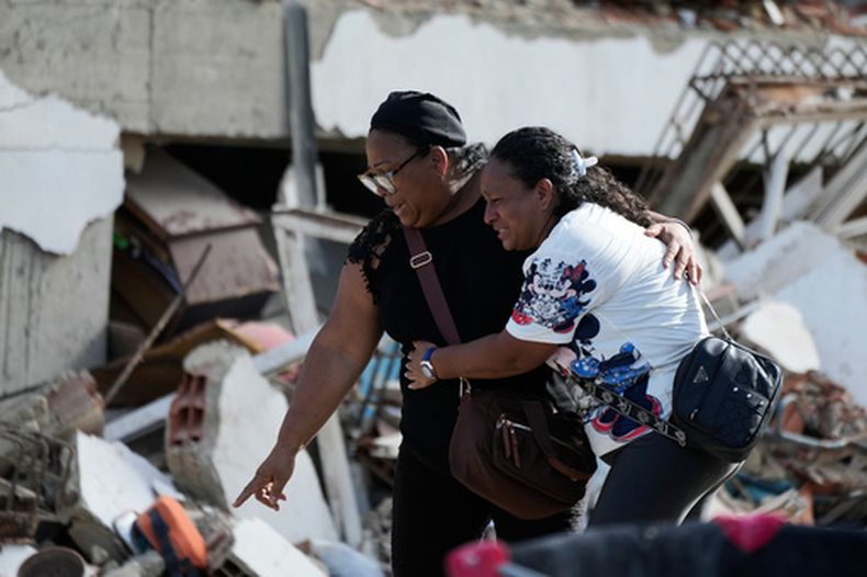 Sobrevivientes señalan un cuerpo atrapado entre los escombros dos días después de que los terremotos azotaran Catia La Mar, Venezuela, el viernes 26 de junio de 2026. (AP foto/Fernando Vergara)