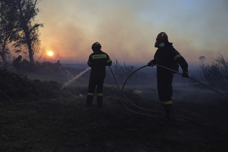 Un grupo de bomberos trabaja para extinguir un incendio forestal en el suburbio de Kryoneri, en el noroeste de Atenas, Grecia, el sábado 26 de julio de 2025. (AP Foto/Yorgos Karahalis)