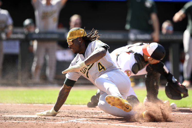Lawrence Butler de los Atléticos se desliza en el home para anotar con el doble de Willie McIver superando al catcher de los Orioles de Baltimore Alex Jackson en la novena entrada el domingo 10 de agosto del 2025. (AP Foto/Nick Wass)