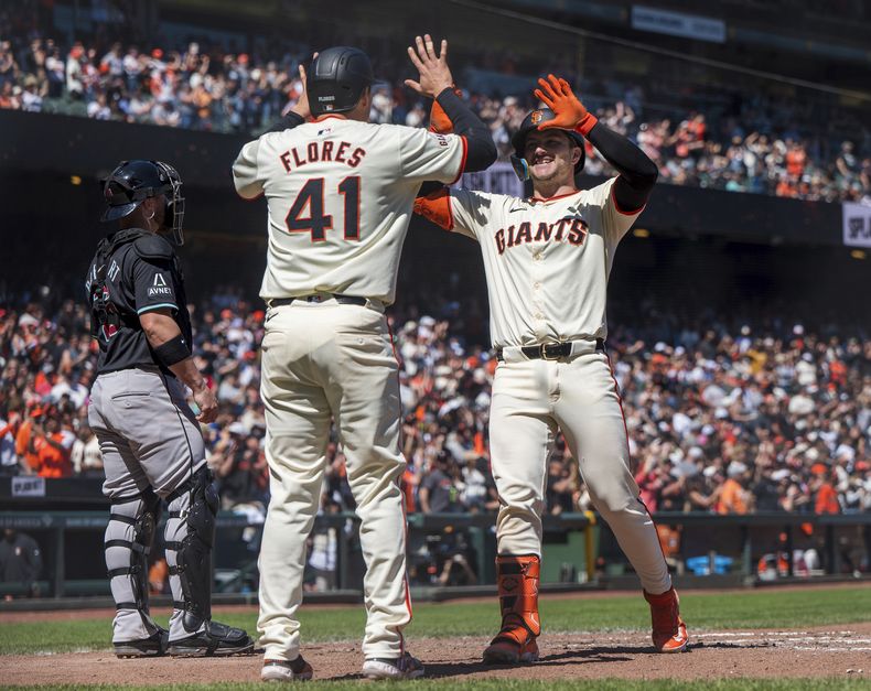 Patrick Bailey, de los Gigantes de San Francisco, es felicitado por su compañero, el venezolano Wilmer Flores, luego de conectar un jonrón ante los Diamondbacks de Arizona, el sábado 20 de abril de 2024 (AP Foto/Nic Coury)