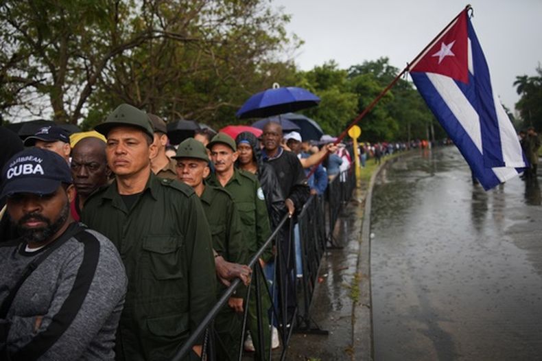 La gente hace cola bajo la lluvia en La Habana, Cuba, el jueves 15 de enero de 2026, frente al Ministerio de las Fuerzas Armadas Revolucionarias, donde se exhiben los restos de los oficiales cubanos que murieron durante la operación estadounidense en Venezuela para capturar al presidente Nicolás Maduro. (Foto AP/Ramón Espinosa)