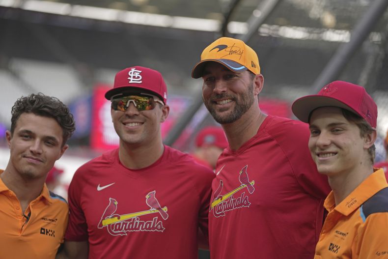 Adam Wainwright de los Cardenales de San Luis posa con los pilotos de F1 Lando Norris de McLaren durante el entrenamiento del equipo el viernes 23 de junio del 2023 antes de la serie del fin de semana ante los Cachorros de Chicago en Londres. (AP Foto/Kin Cheung)