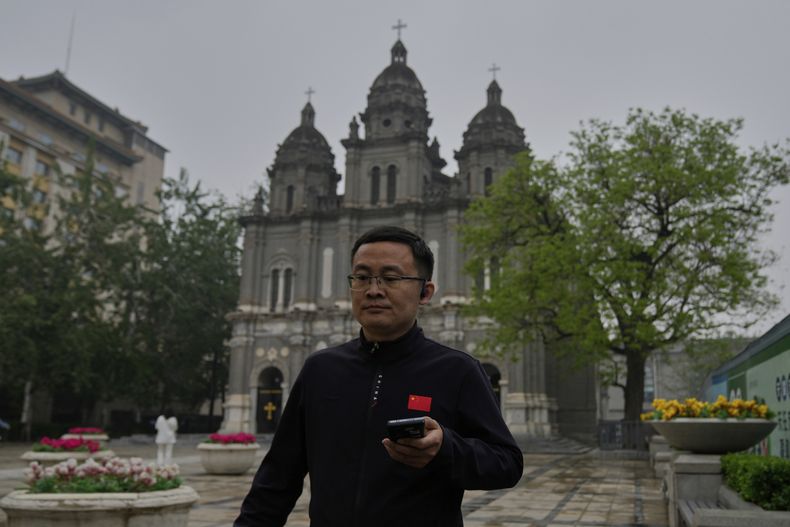 Un hombre con una camisa con la bandera china pasa frente a la iglesia católica Wangfujing, también conocida como la iglesia del Este, en Beijing, el lunes 21 de abril de 2025. (AP Foto/Ng Han Guan)