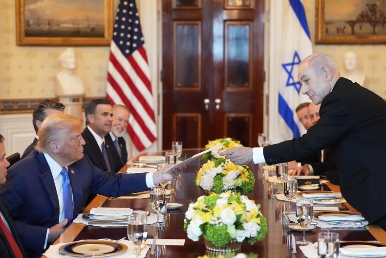 El primer ministro israelí Benjamin Netanyahu, derecha, le entrega al presidente Donald Trump una carpeta durante una reunión en el Salón Azul de la Casa Blanca, el lunes 7 de julio de 2025, en Washington. (AP Foto/Alex Brandon)