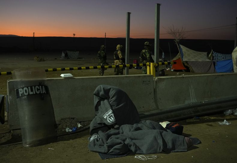 Una familia migrante espera en la frontera con Chile, en Tacna, Perú, sin poder cruzar, la madrugada del viernes 28 de abril de 2023. (AP Foto/Martín Mejía)