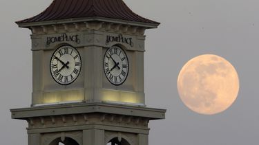 La Luna vista detrás de la torre de Home Place, el sábado 22 de junio de 2013, en Prattville, Alabama. (AP Foto/Dave Martin, Archivo)