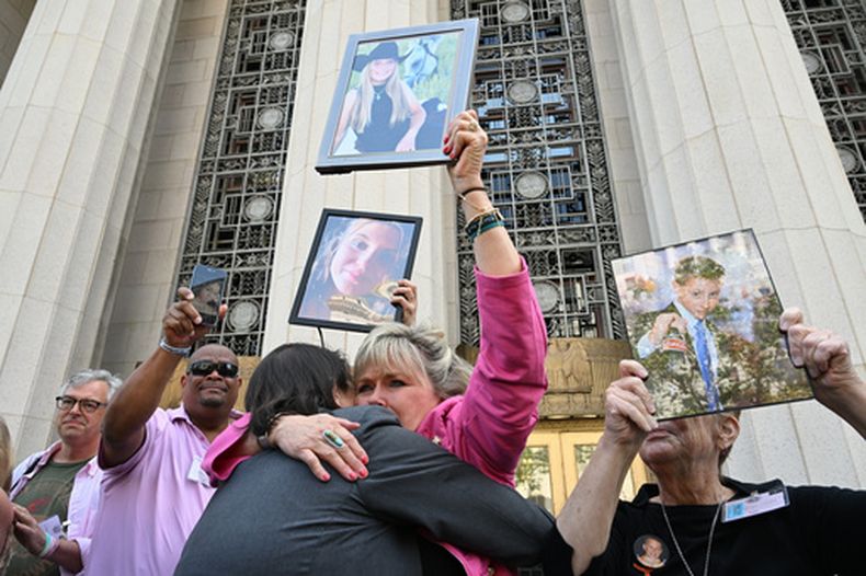 Lori Schott, centro, sostiene una foto de su hija Annalee Schott, tras el veredicto en un trascendental juicio sobre si las redes sociales vuelven adictos y perjudican deliberadamente a los menores en el Tribunal Superior de Los Ángeles, el miércoles 25 de marzo de 2026, en Los Ángeles. (AP Foto/William Liang)