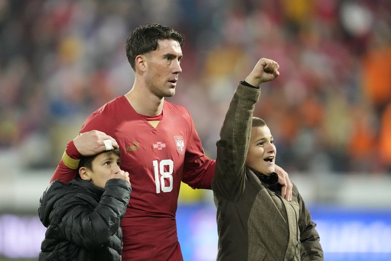 El delantero serbio Dusan Vlahovic reacciona junto a sus hijos tras el empate 2-2 contra Bulgarias en las eliminatorias de la Eurocopa, el domingo 19 de noviembre de 2023, en Leskovac, Serbia. (AP Foto/Darko Vojinovic)
