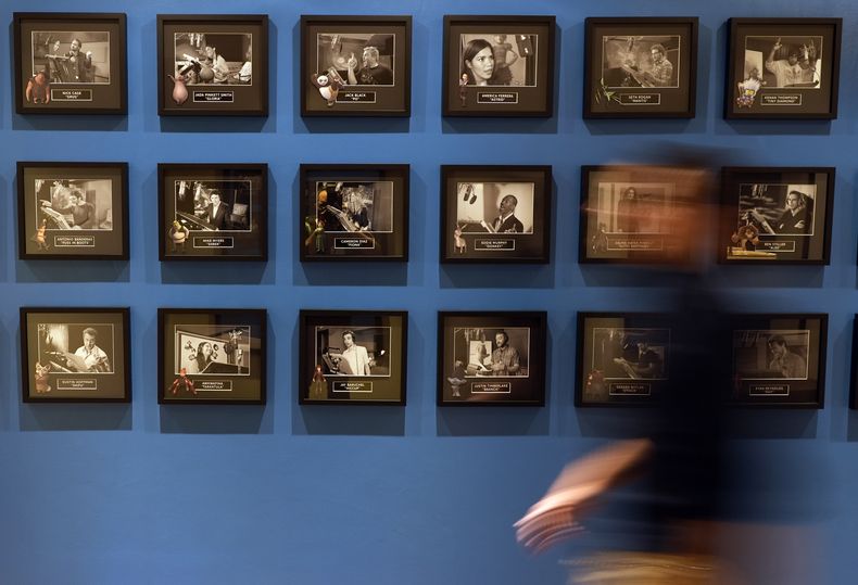 Un empleado pasa junto a una pared con fotografías de miembros famosos de elencos de voces de las películas de DreamWorks Animation el miércoles 25 de septiembre de 2024, en DreamWorks Animation en Glendale, California. (Foto AP/Chris Pizzello)