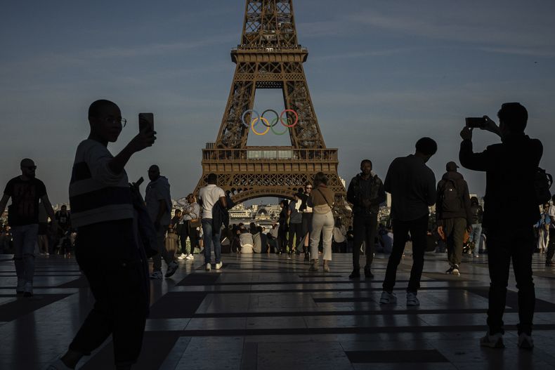 ARCHIVO - Varias personas utilizan sus celulares para fotografiar los anillos olímpicos en la Torre Eiffel, en París, el 7 de junio de 2024, en París. (AP Foto/Aurelien Morissard, archivo)