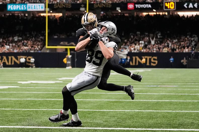 Brock Bowers (89), ala cerrada de los Raiders de Las Vegas, atrapa un pase de anotación con el safety Jonas Sanker, colgado, de los Saints de Nueva Orleans, intentando evitarlo durante la segunda mitad del juego de la NFL, el domingo 27 de septiembre de 2026, en Nueva Orleans. (AP Foto/Gerald Herbert)