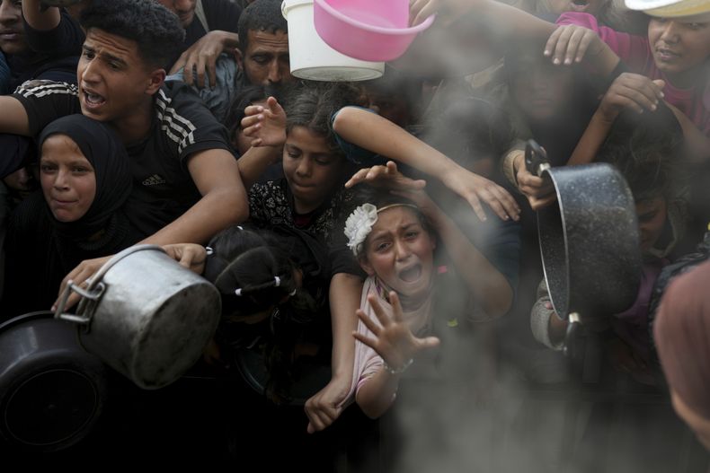 Una niña palestina forcejea junto a otras personas para tratar de conseguir comida donada en un centro de distribución en Beit Lahiya, en el norte de la Franja de Gaza, el domingo 16 de marzo de 2025. (AP Foto/Abdel Kareem Hana)