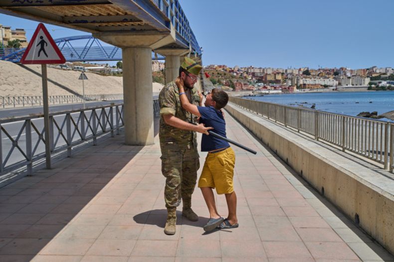 Un niño de 12 años que cruzó hacia España sin la compañía de un adulto es escoltado por un soldado español hacia la frontera con Marruecos mientras el niño le suplica que no sea enviado de regreso, el lunes 3 de agosto de 2026, en el territorio español de Ceuta. (AP Foto/Bernat Armangue)