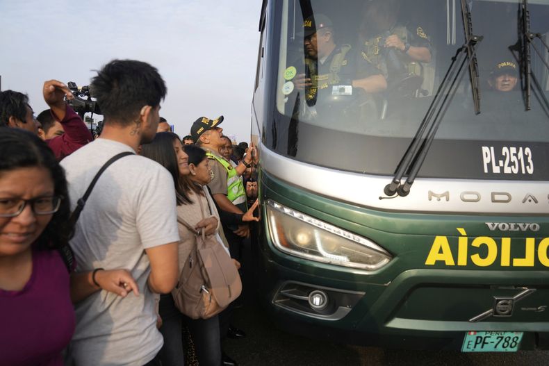 Los viajeros luchan por abordar un autobús policial durante una huelga de transporte contra las extorsiones a las empresas de transporte en las afueras de Lima, Perú, el jueves 10 de abril de 2025. (AP Foto/Martín Mejía)