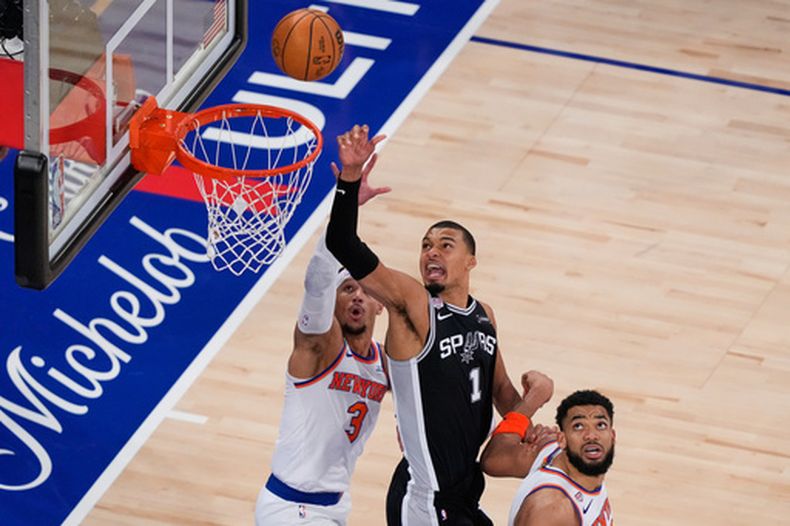 Victor Wembanyama (1), de los Spurs de San Antonio, dispara mientras Josh Hart (3) y Karl-Anthony Towns (32), de los Knicks de Nueva York defienden durante la segunda mitad del tercer juego de las Finales de la NBA, el lunes 8 de junio de 2026, en Nueva York. (AP Foto/Yuki Iwamura)