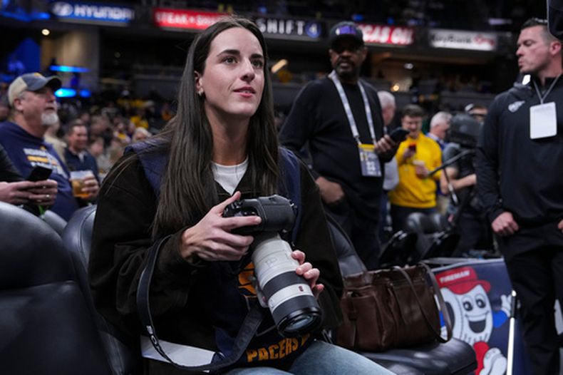 Caitlin Clark, del Fever de Indiana, toma fotografías previo al inicio del partido de baloncesto de la NBA entre los Pacers de Indiana y los Lakers de Los Ángeles, el miércoles 25 de marzo de 2026, en Indianápolis. (AP Foto/Michael Conroy)