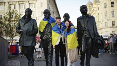 Aficionados colocan una bandera de Ucrania a una estatua en homenaje a los Beatles, antes de Eurovisión, en Liverpool, Inglaterra, el 12 de mayo de 2023. (Aaron Chown/PA via AP)