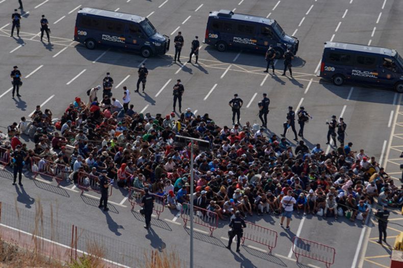 Migrantes que cruzaron la frontera desde Marruecos a España son escoltados por la policía española hacia refugios temporales tras ser retirados de una playa en el enclave ibérico de Ceuta, el jueves 20 de agosto de 2026. (AP Foto/Antonio Sempere)