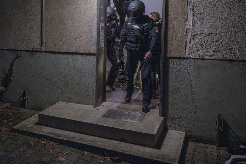 Agentes de policía salen de una vivienda durante un cateo de madrugada, en Munich, Alemania, el 21 de noviembre de 2023. (Peter Kneffel/dpa vía AP)
