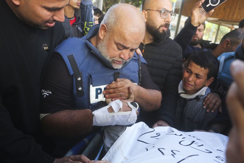El periodista Wael Dahdouh, centro, de Al Jazeera, sostiene la mano de su hijo Hamza, que también trabajaba para Al Jazeera y quien murió en un ataque israelí en Rafah, en la Franja de Gaza, el domingo 7 de enero de 2024. (AP Foto/Hatem Ali)
